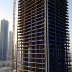 Towering skyscraper under construction with steel beams in a GCC city, showcasing metal fabrication certifications like ISO 9001 and AWS D1.1 for safety and quality.